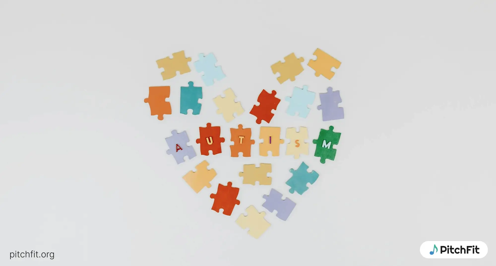 A heart made of colorful puzzle pieces with 'Autism' spelled out