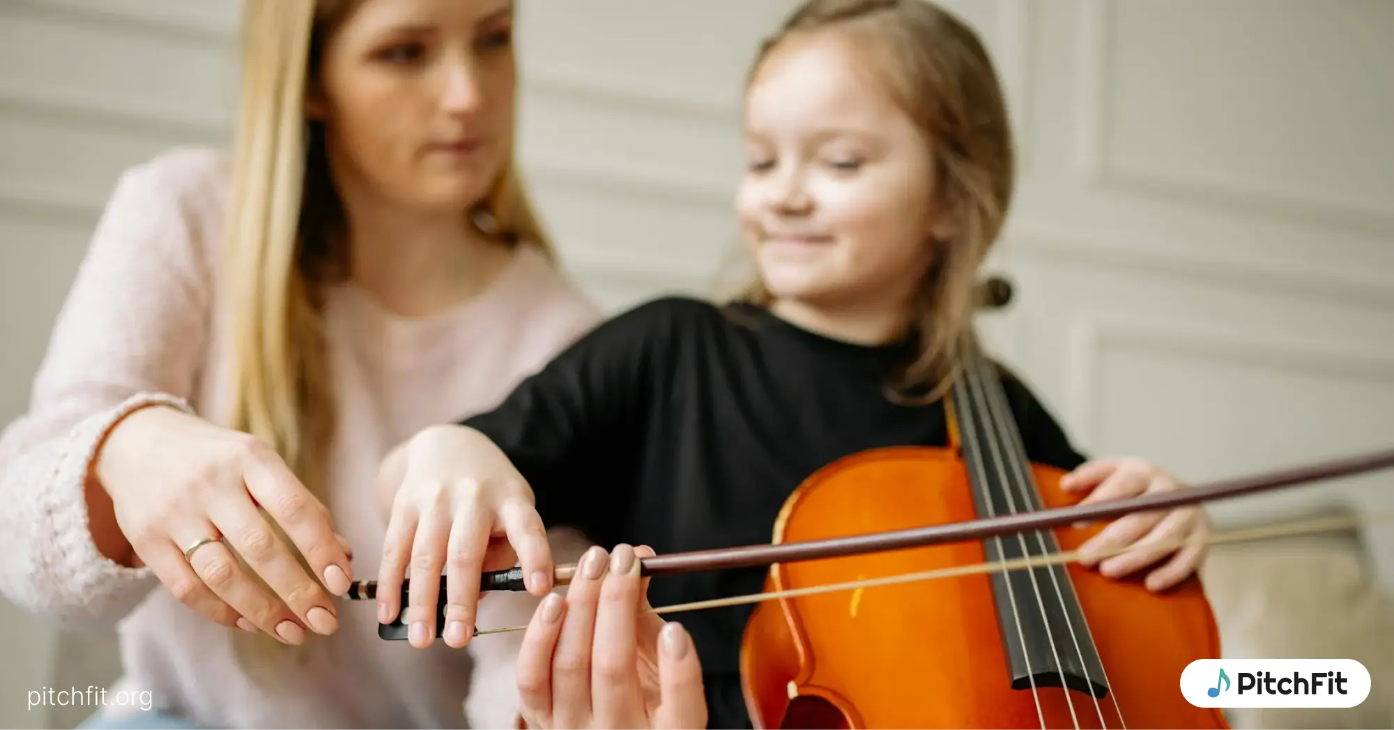 A girl learning violin with her instructor staying behind